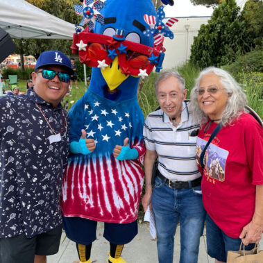 Steve Rhee posing a picture with Purdy the Peacock and residents.
