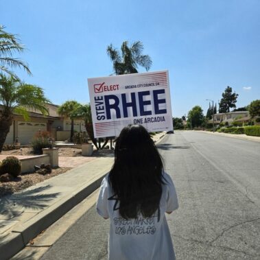 Lady walking with Elect Steve Rhee sign in a neighborhood.
