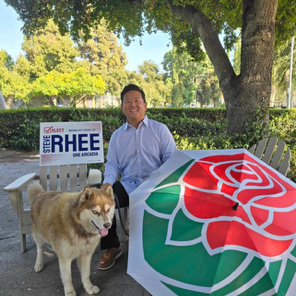Steve Rhee sitting with his dog with Rose Parade umbrella.