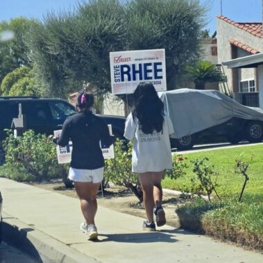 Two ladies walking with Elect Steve Rhee sign in a neighborhood.