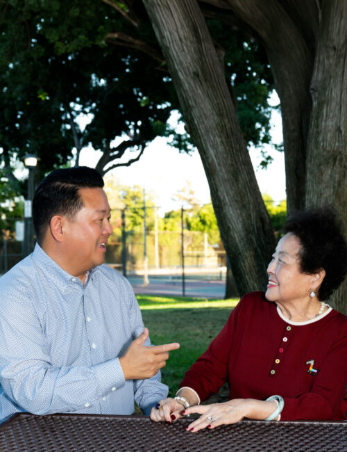 Steve Rhee sitting with his mom at a table in the park.